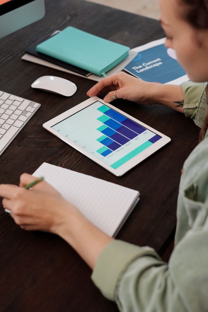 why-choose-us Focused person working on digital tablet analyzing business graphs at desk.