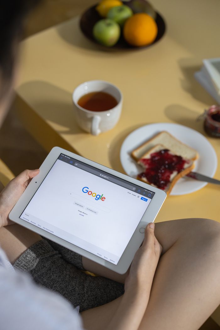 services-cta Person using a tablet with Google search open while having breakfast with toast and tea.